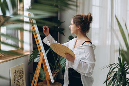 Female artist drawing with brush on canvasの写真素材