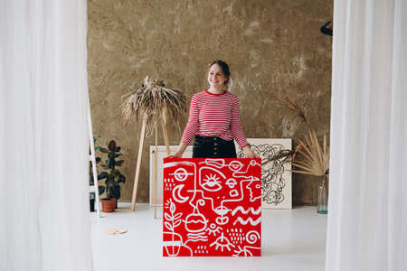 Happy artist standing at studio with abstract drawingの写真素材