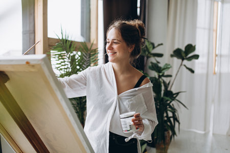 Smiling female painter drawing on easelの写真素材
