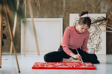 Beautiful woman painting in red canvas at art studioの写真素材