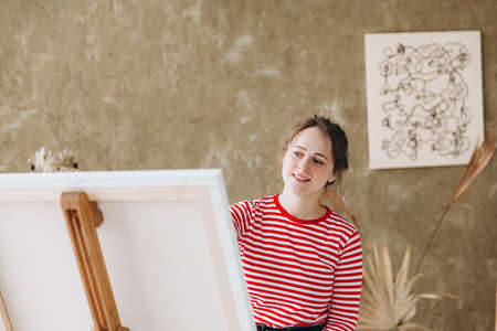 Creative woman sitting on chair and painting in easelの写真素材