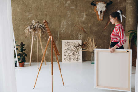 Talented woman carrying canvas for painting at studioの写真素材