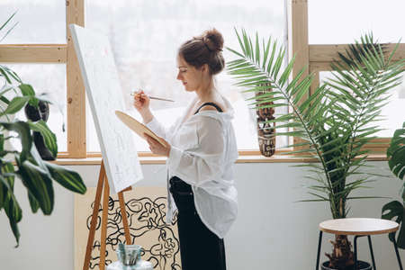 Woman using brush and color palette for drawingの写真素材