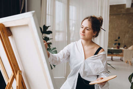 Inspired female artist drawing on canvas indoorsの写真素材