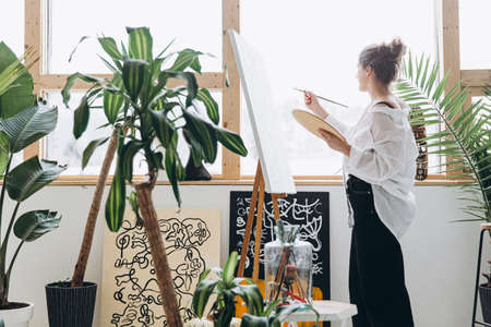Creative female artist painting with brush on canvasの写真素材