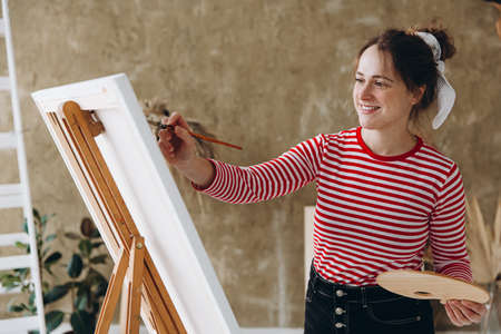 Smiling artist using brush and color palette for drawingの写真素材