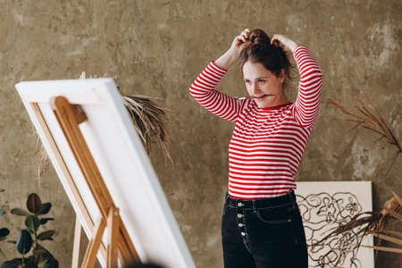 Female artist tying hair before painting on canvasの写真素材
