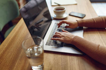 Woman working on laptop with cup of coffee on tableの写真素材
