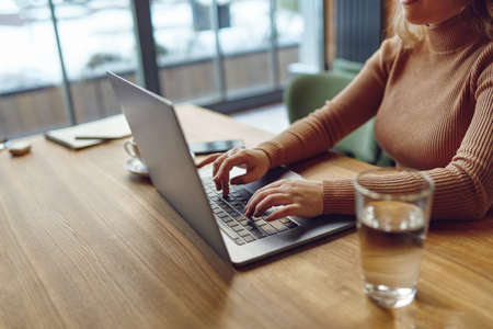 Woman typing on laptop while working remotely from cafeの写真素材