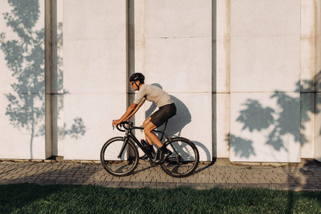 Smiling caucasian man in sport clothes, helmet and glasses practicing in cycling at urban area....