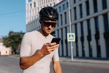 Caucasian male athlete taking break outdoors during morning cyclist. Positive young man sitting on...
