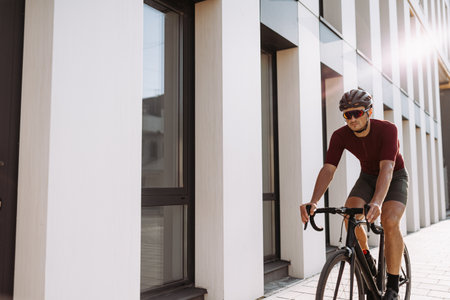 Caucasian male athlete taking break outdoors during morning cyclist. Positive young man sitting on bike and looking aside. Favorite sport hobby.の写真素材