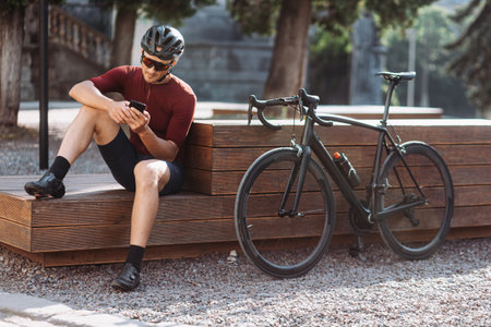 Sporty young man in helmet and glasses spending morning time for outdoors training on black sport bike. Professional cyclist spending every free moment for workout.の写真素材
