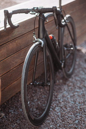 Close up of muscular caucasian man in sport clothes using black bike for practicing in cycling...
