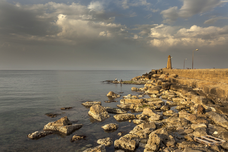 Pier with lighthouse and fishermen in early evening in Kyrenia (Girne)の写真素材