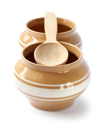 Glazed ceramic pots for cooking with wooden spoon on a white background with clipping pathの写真素材
