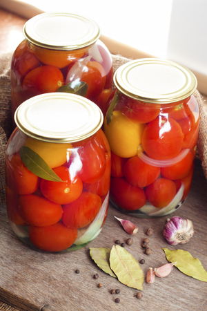 Glass jars with homemade pickled tomatoes, sealed with metal lidの写真素材