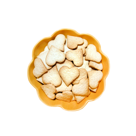 Ginger cookies in the shape of heart in a yellow bowl isolated on white background with clipping pathの写真素材