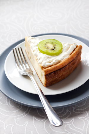 Homemade cottage cheese cake with kiwi fruit and cream on a plateの写真素材