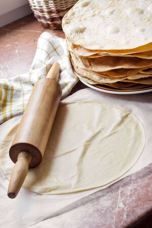 Cooking multi-layered cake Napoleon - baked cake layers, raw dough and wooden rolling pinの写真素材