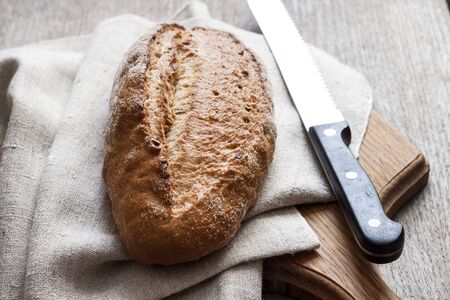 Loaf of whole wheat bread wooden board on kitchen tableの写真素材