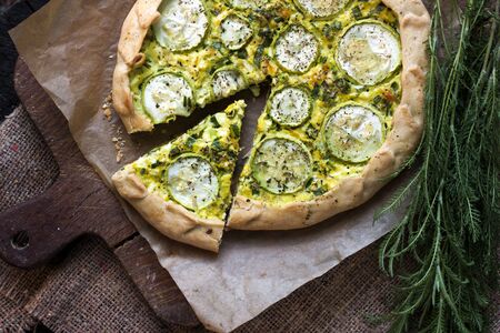 Homemade courgette and goat cheese pie on a dark rustic wooden board background. Rustic style food. Flat lay, top viewの写真素材