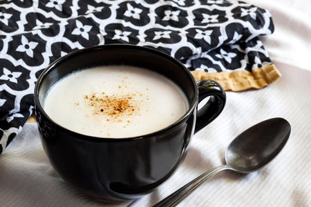 Cauliflower Soup (Creme du Barry) in black bowl on white background with black and white cloth