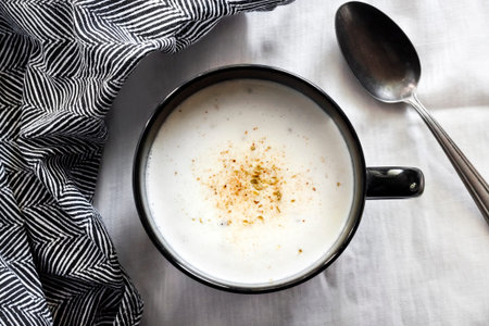Cauliflower Soup (Creme du Barry) in black bowl on white background with black and white cloth....