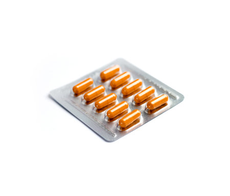 Orange pill capsules in blister pack isolated on white background, shallow depth