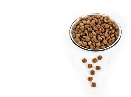 Dry pet food in a white ceramic bowl isolated on white background. Copy spaceの写真素材