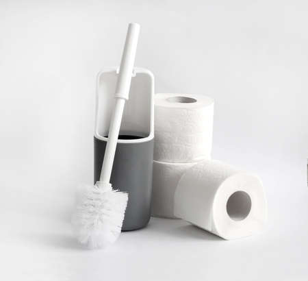 White and gray plastic toilet brush and roll of toilet paper on white backgroundの写真素材