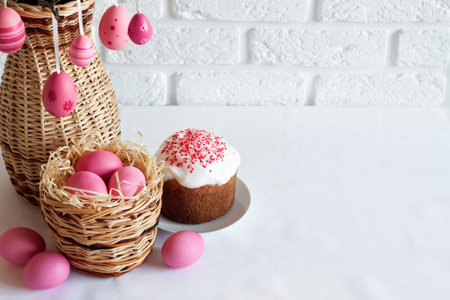 Easter composition with decorated tree branches in a wicker vase, pink colored eggs in wicker basket...