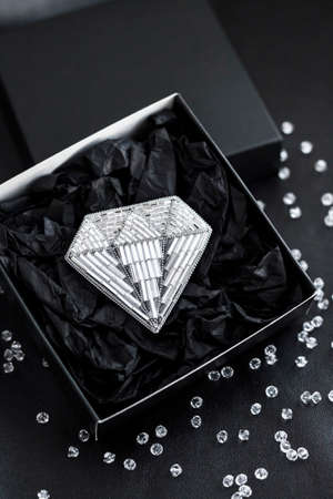 Seed beads embroidered brooch in a shape of diamond in black gift box on black backgroundの写真素材