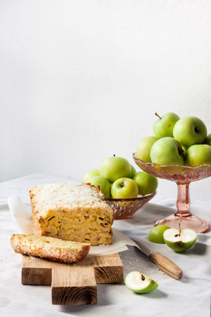 Apple and coconut loaf cake and apples in a vase on a table. Copy spaceの写真素材