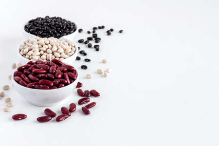 Assortment of beans in a white bowl on white background. Red kidney beans, white beans and black beansの写真素材