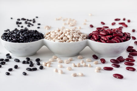 Assortment of beans in a white bowl on white background. Red kidney beans, white beans and black beansの写真素材
