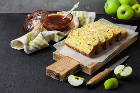Sliced apple and coconut oaf cake on wooden cutting board on dark backgroundの写真素材
