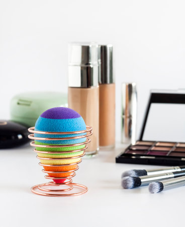 Set of decorative cosmetics on a white background. Rainbow beauty egg sponge on a stand in the foregroundの写真素材
