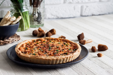 Quiche - open tart pie with morel mushrooms, onion and cheese on a plate