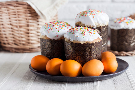 Decorated Easter cakes and orange colored eggs on a plate on the table.