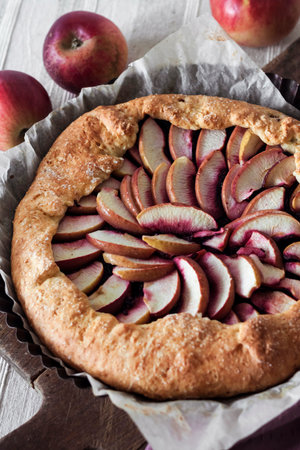 Close-up of sweet galette with apples and elder berries on wooden board.の写真素材