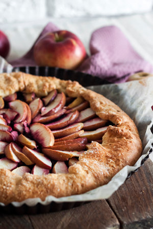 Close-up of sweet galette with apples and elder berries on wooden board.の写真素材