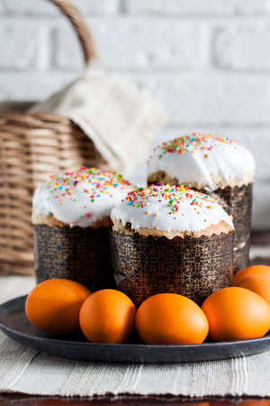Close-up of glaze decorated Easter cakes and orange colored eggs on a plate.の写真素材