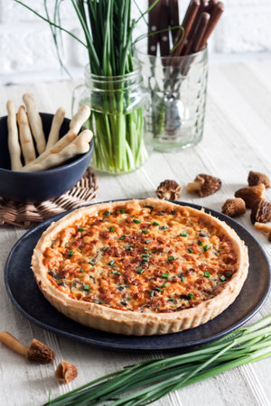 Quiche - open tart pie with morel mushrooms, onion and cheese on a plateの写真素材
