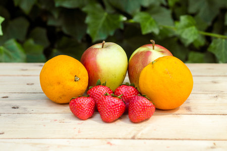 Apples, oranges and strawberries on wooden table top view
