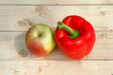 Red pepper and apple on wooden backgroundの写真素材