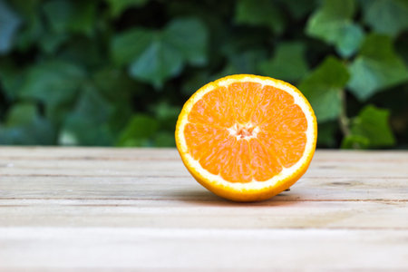 Fresh ripe orange on wooden background. Exotic juicy mellow fruit. In the background is green ivy plantの写真素材