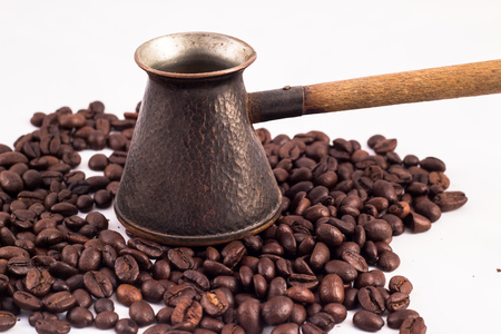 Armenian Jazva, small pot for making coffee. Many coffee beans in the background. Texture of the coffee beans on a white background. Smelly, saturated brown arabic coffee beansの写真素材