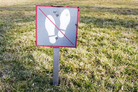 Don't walk on the grass sign on a crooked poleの写真素材