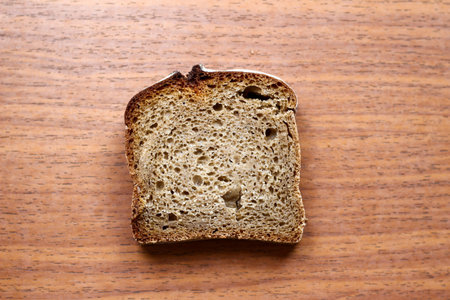 Piece of dark wholegrain bread on wooden background